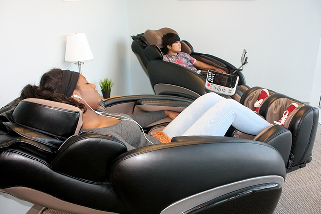 Two students relaxing in massage chairs 