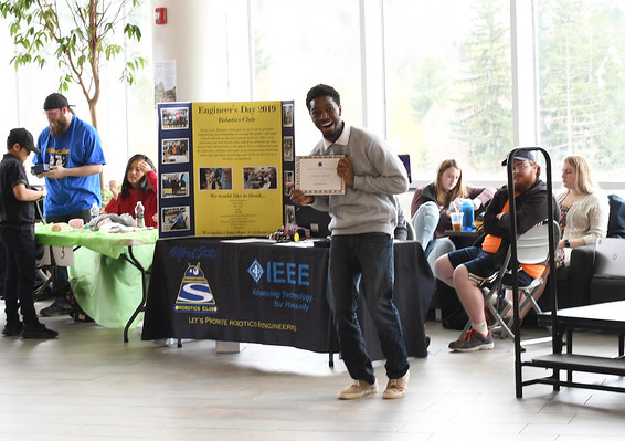 student holding a certificate in front of a poster board on a table