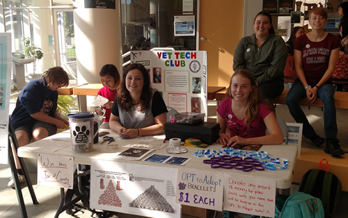 students sitting at a table selling items for a fundraiser